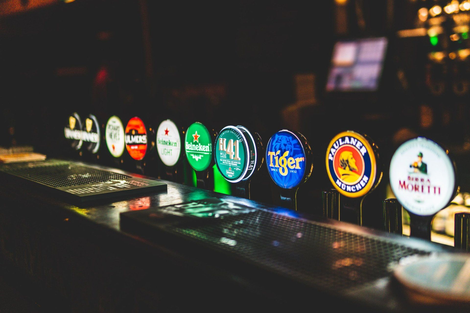 a row of beer taps including heineken and paulaner