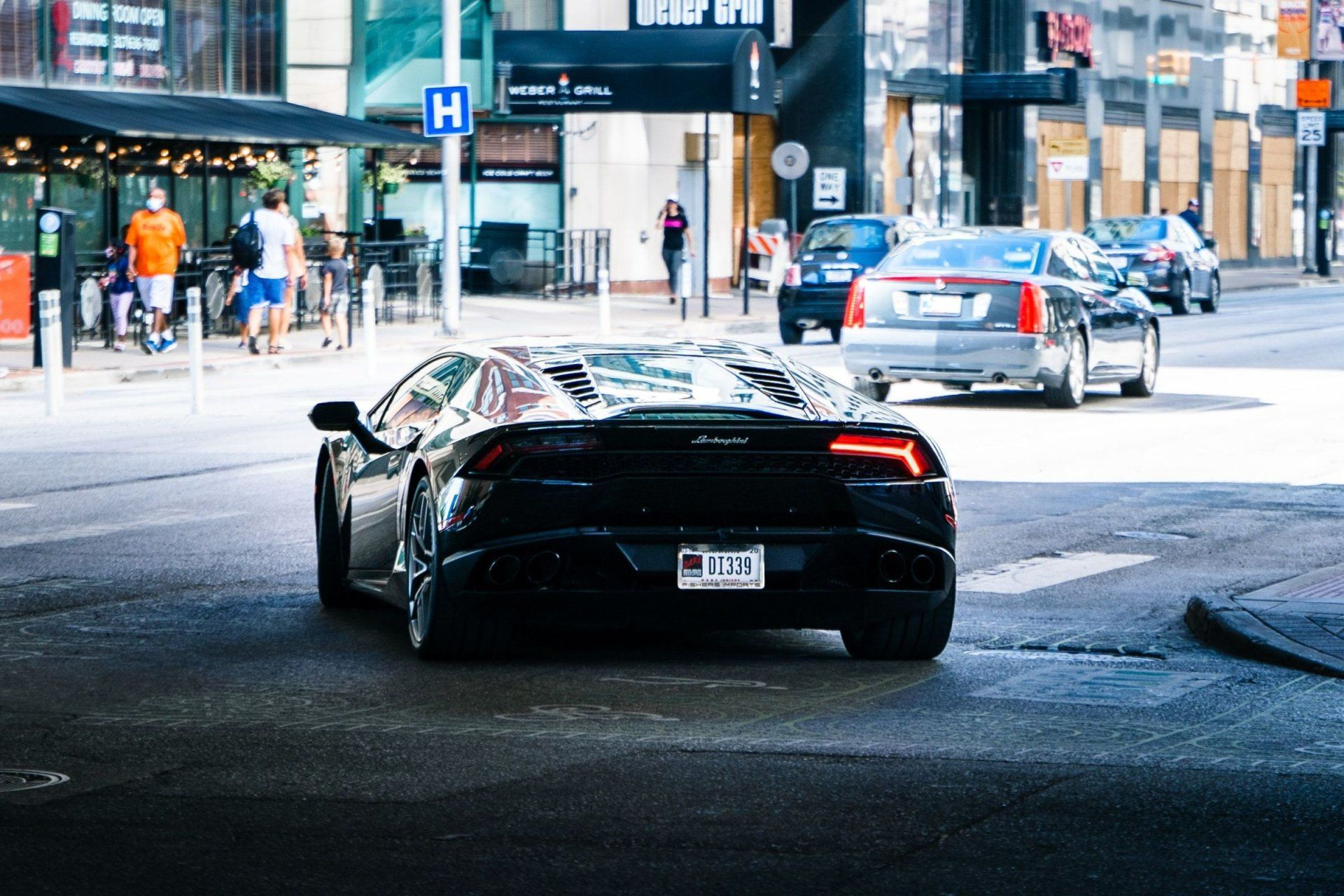 a black lamborghini is driving down a city street