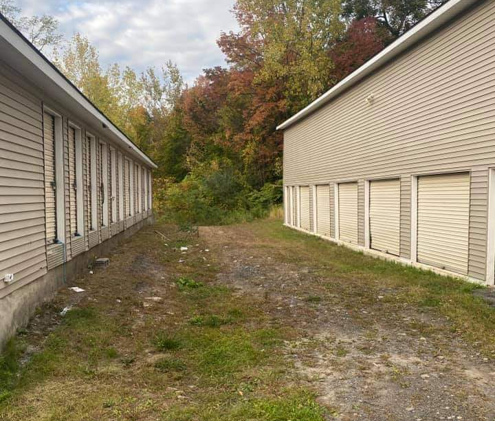 a row of storage units are lined up next to each other on a dirt road .