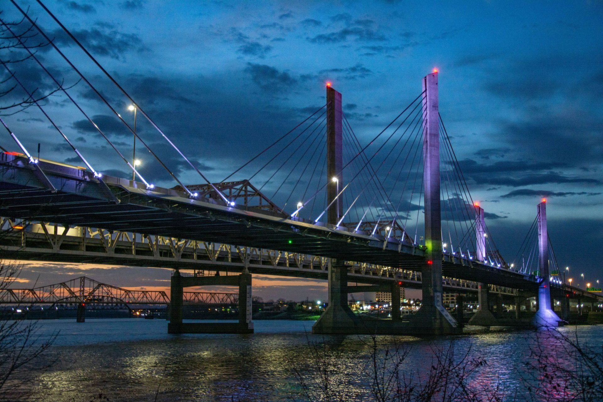 a bridge over a body of water is lit up at night