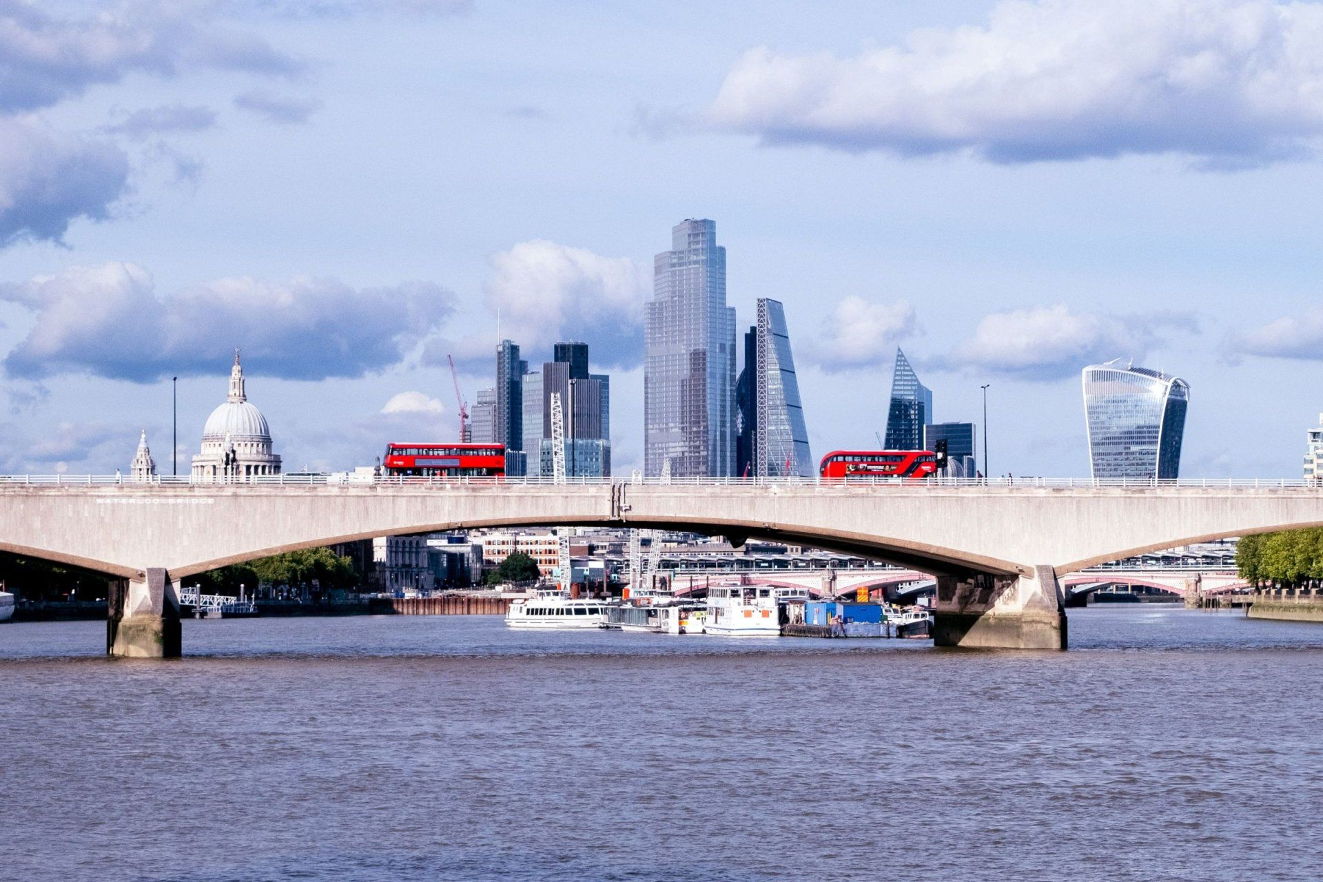 a red double decker bus is crossing a bridge over a river