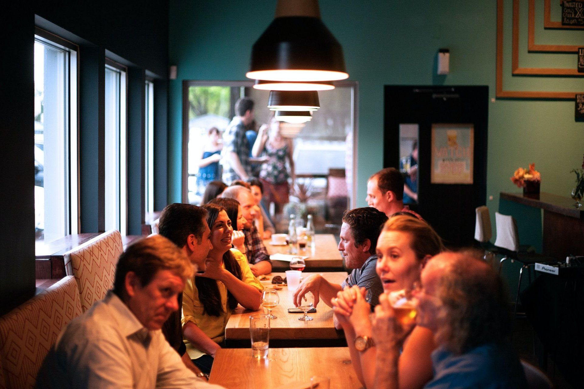 a group of people are sitting at tables in a restaurant with a sign on the wall that says 