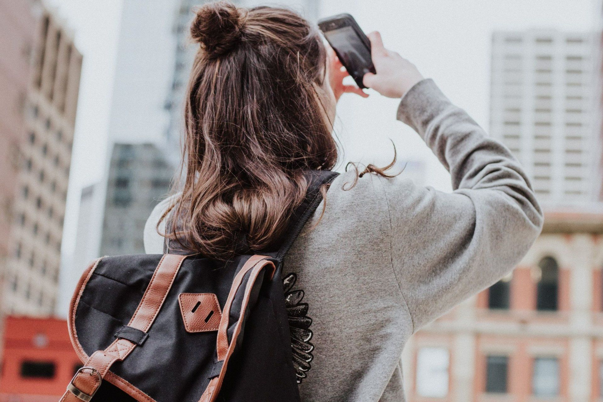 a woman with a backpack is taking a picture with her phone