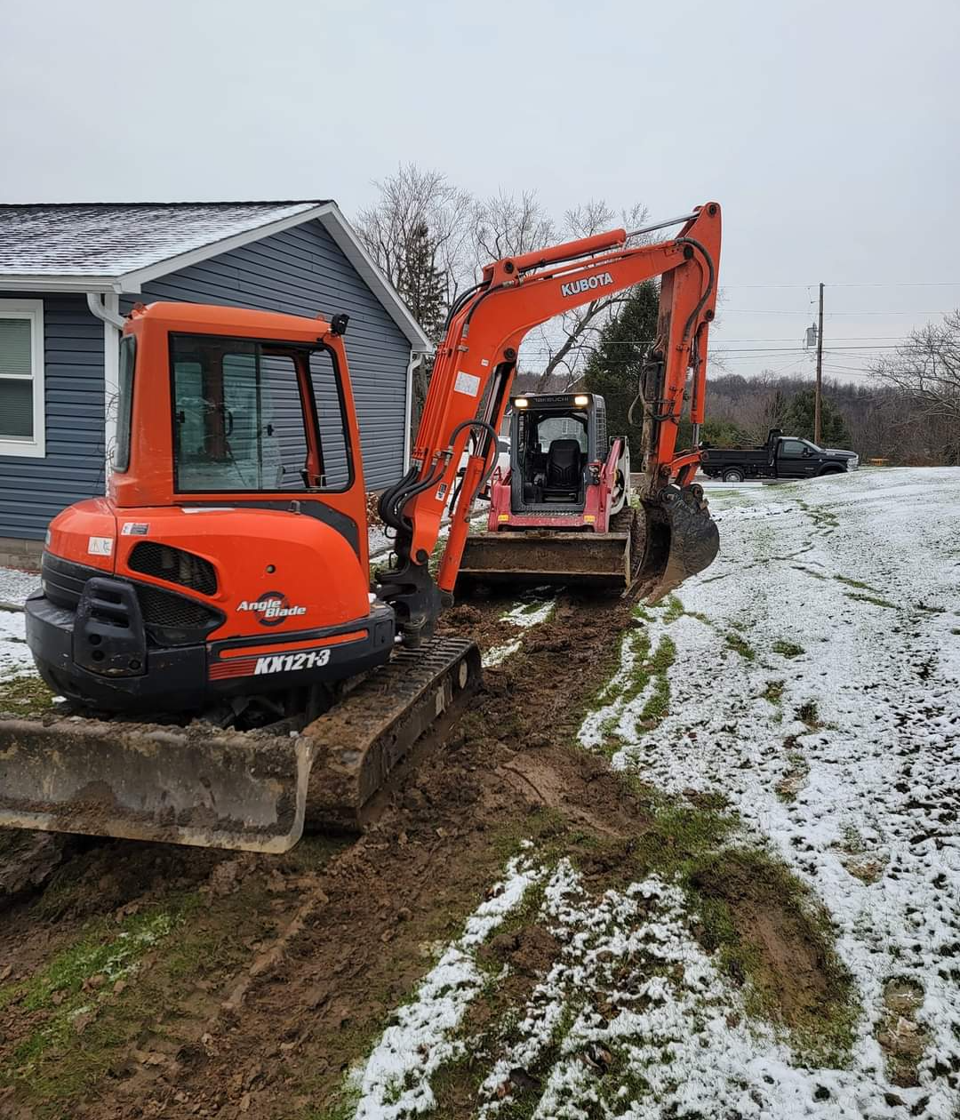 an orange kubota excavator sits in front of a house