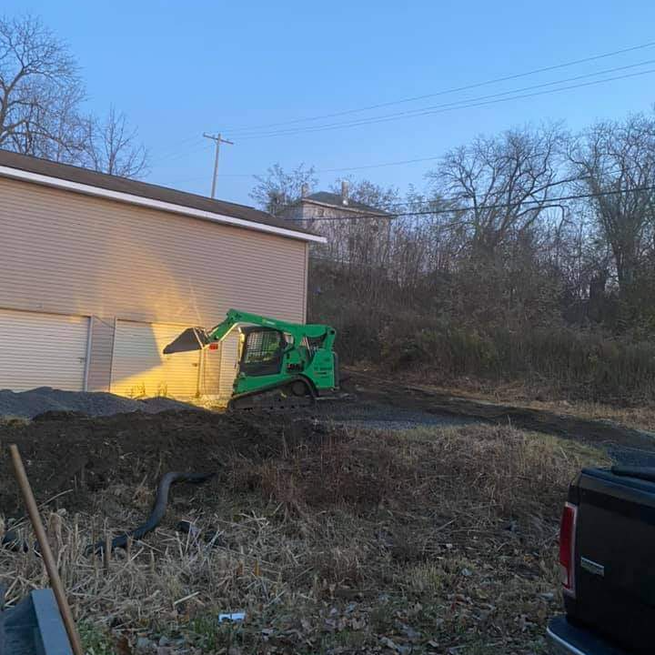 a green forklift is moving dirt in front of a building .