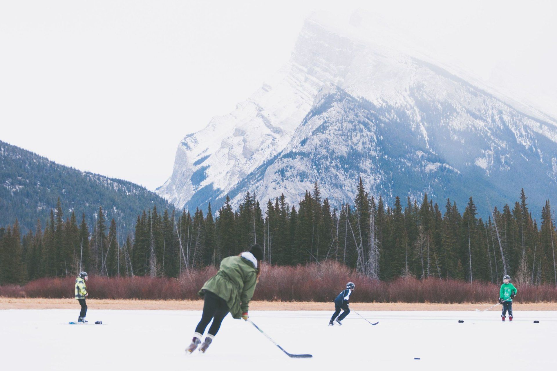 a group of people are playing ice hockey in the mountains