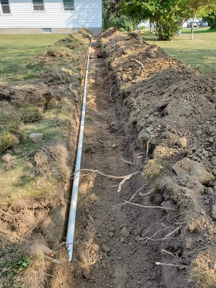 a drain pipe is being installed in the dirt in front of a house .