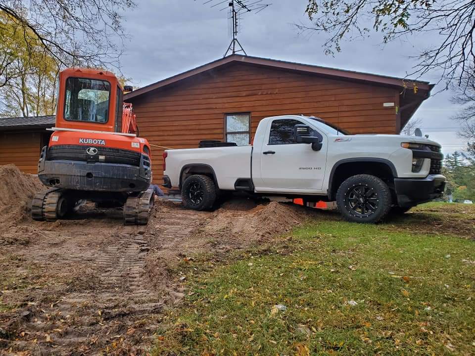 a kubota excavator sits next to a white truck