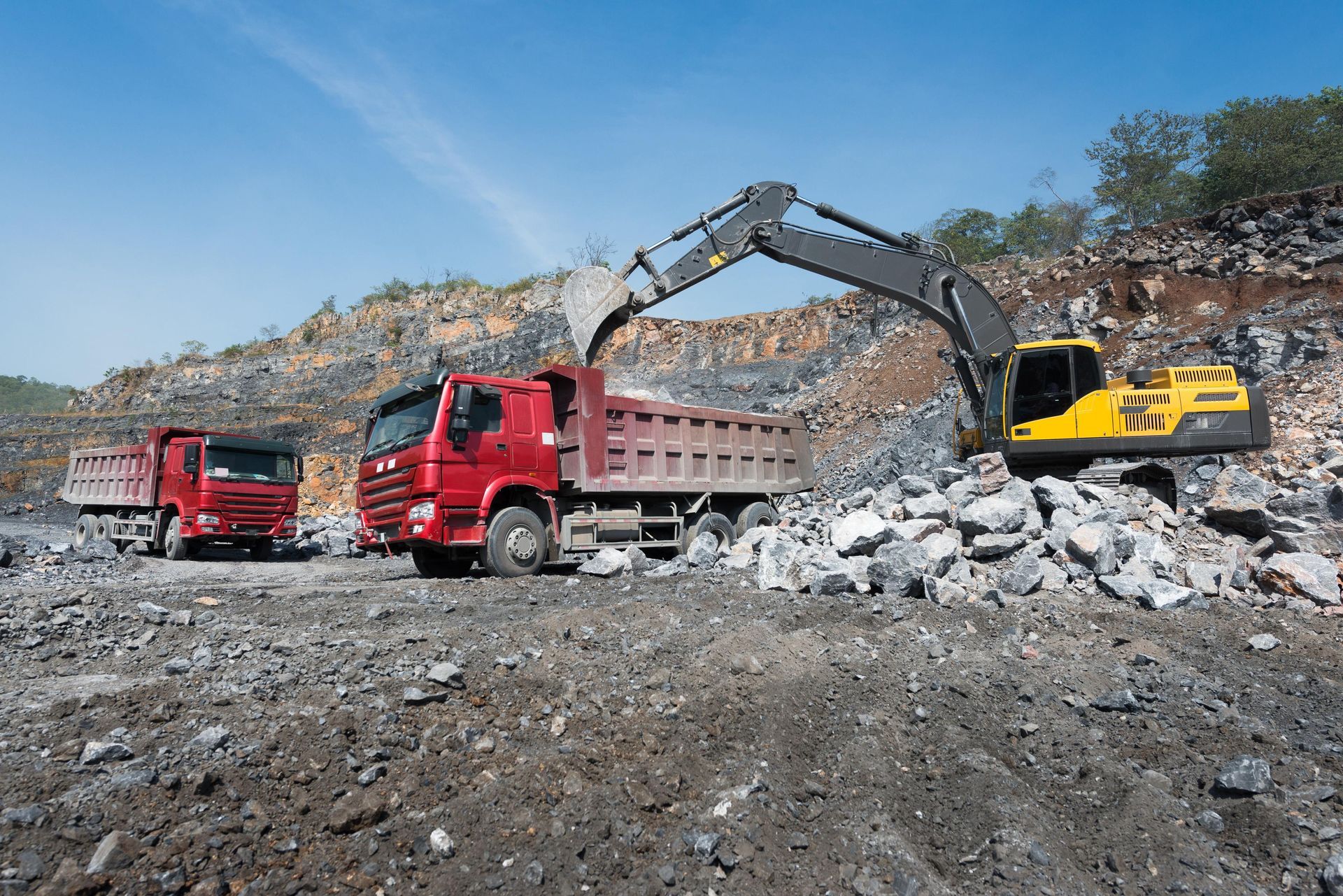 A dump truck is being loaded with rocks by an excavator in a quarry.