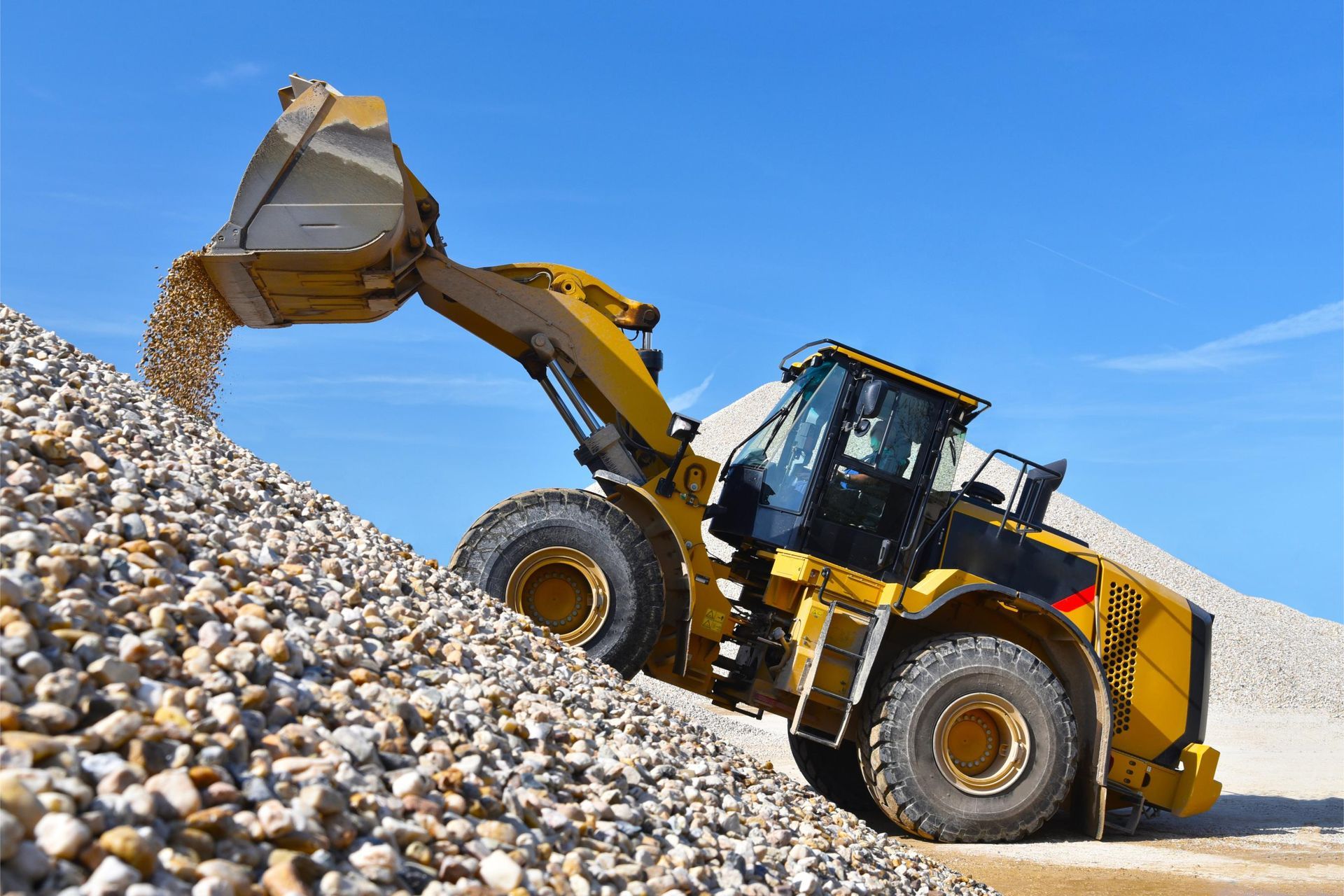 A bulldozer is loading gravel into a pile of gravel.