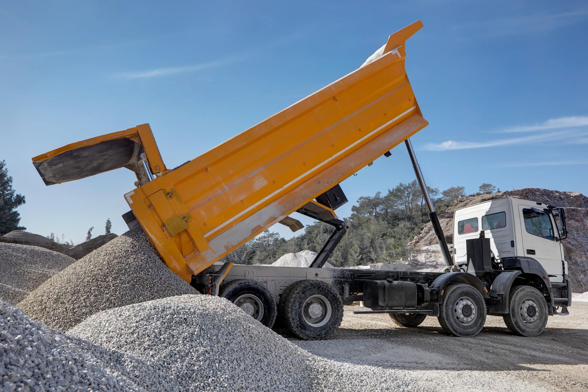 A dump truck is being loaded with gravel in a quarry.