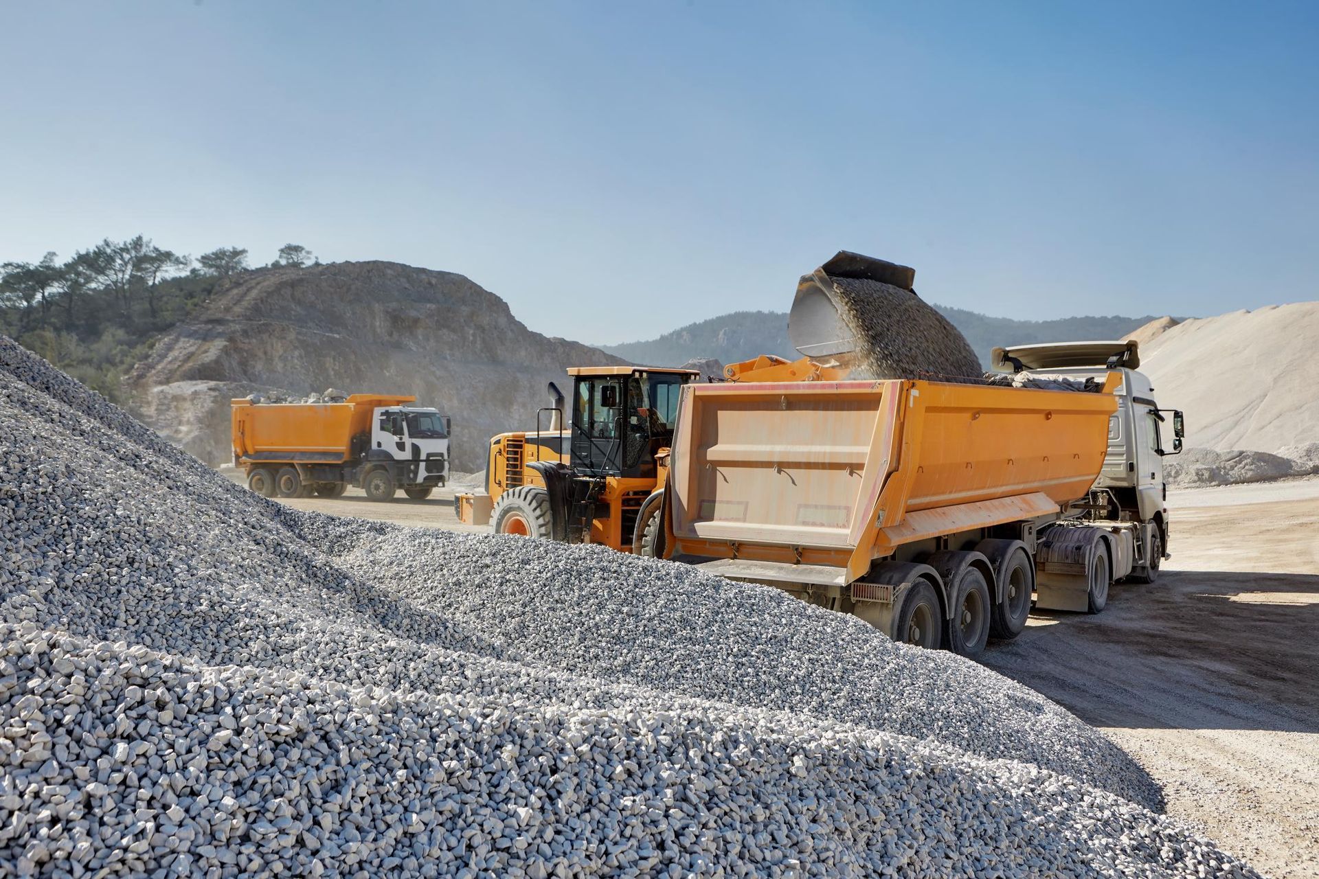 A dump truck is being loaded with gravel in a quarry.