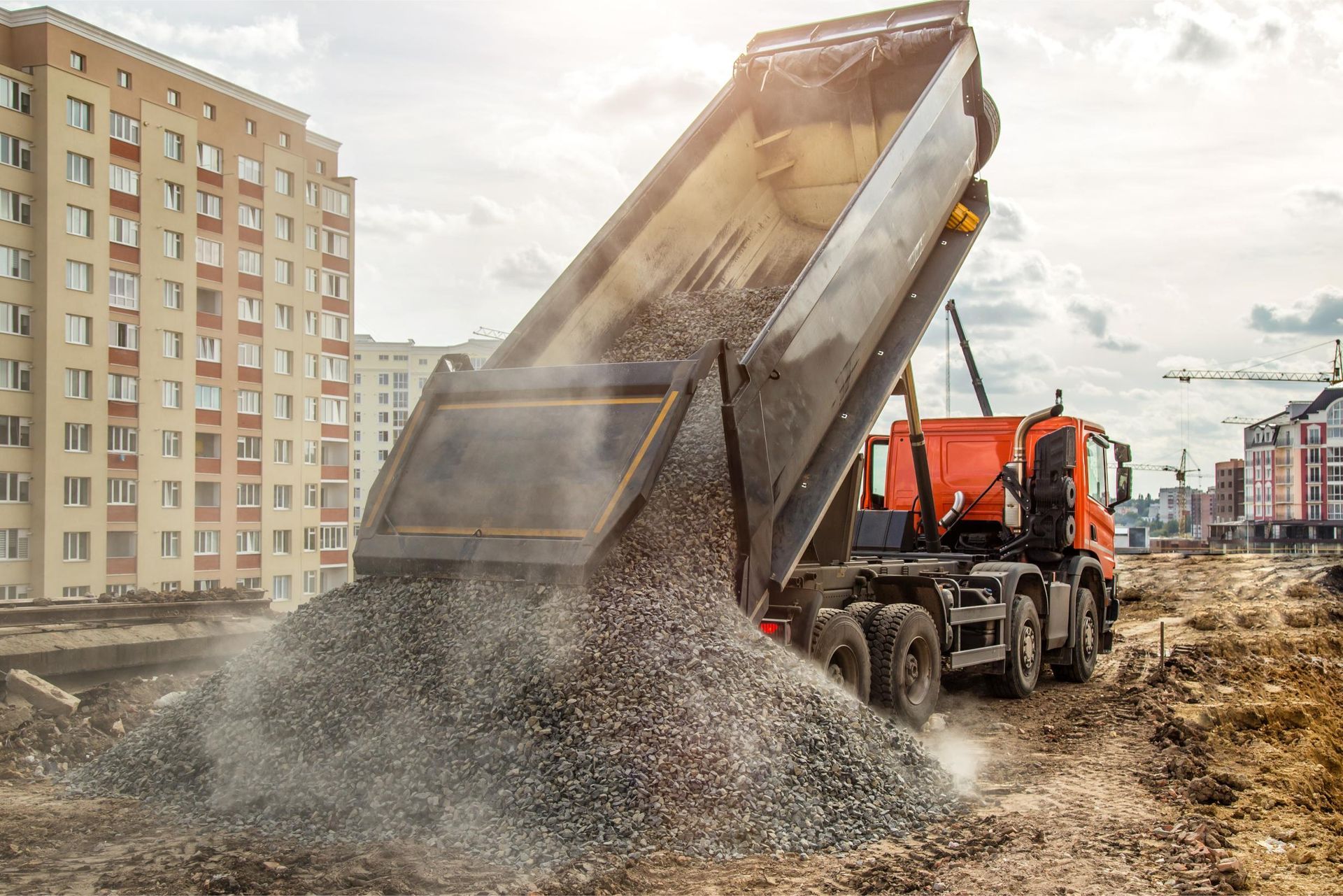 A dump truck is dumping gravel on a construction site.