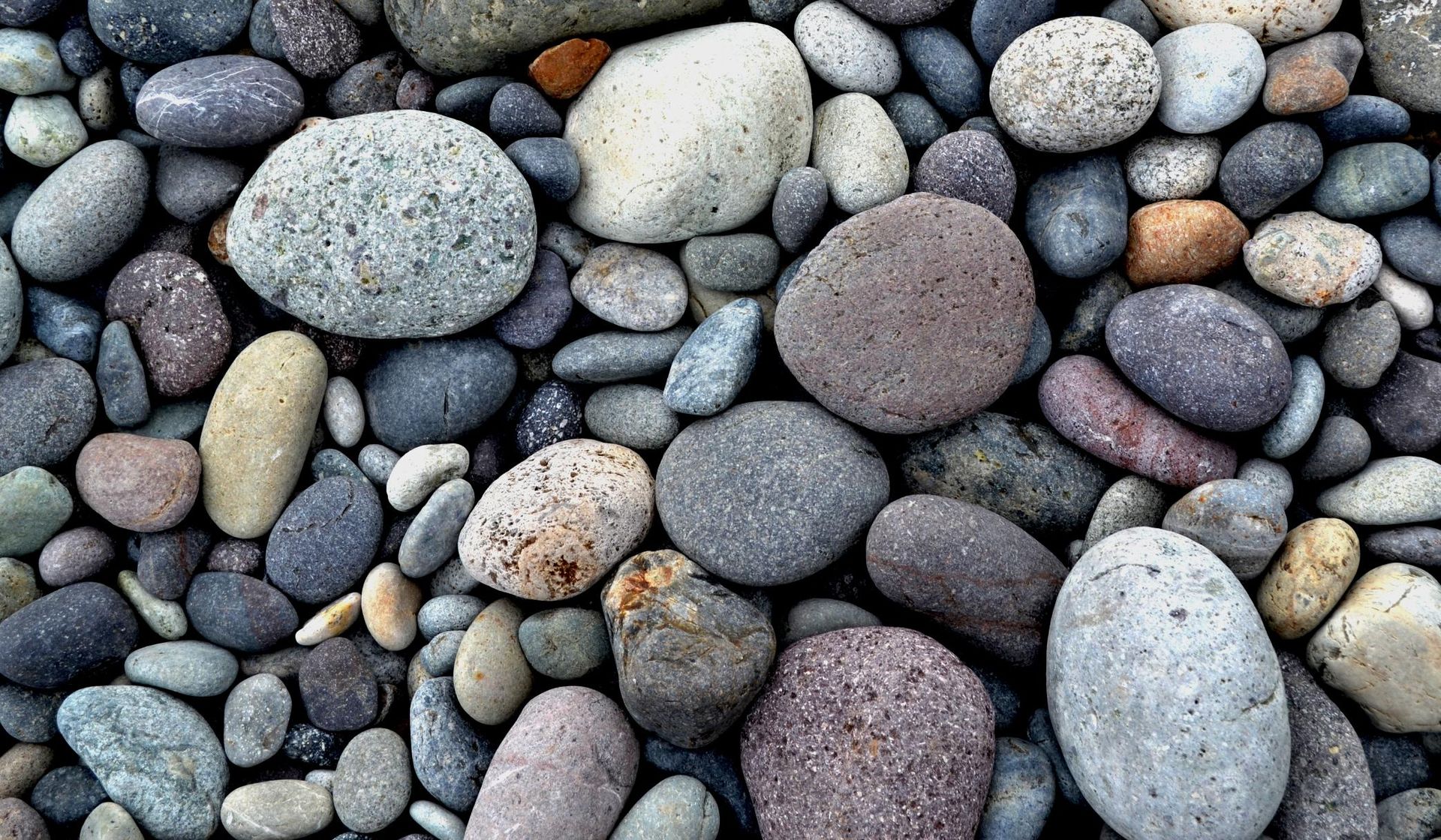 A pile of rocks of different sizes and colors on a beach.