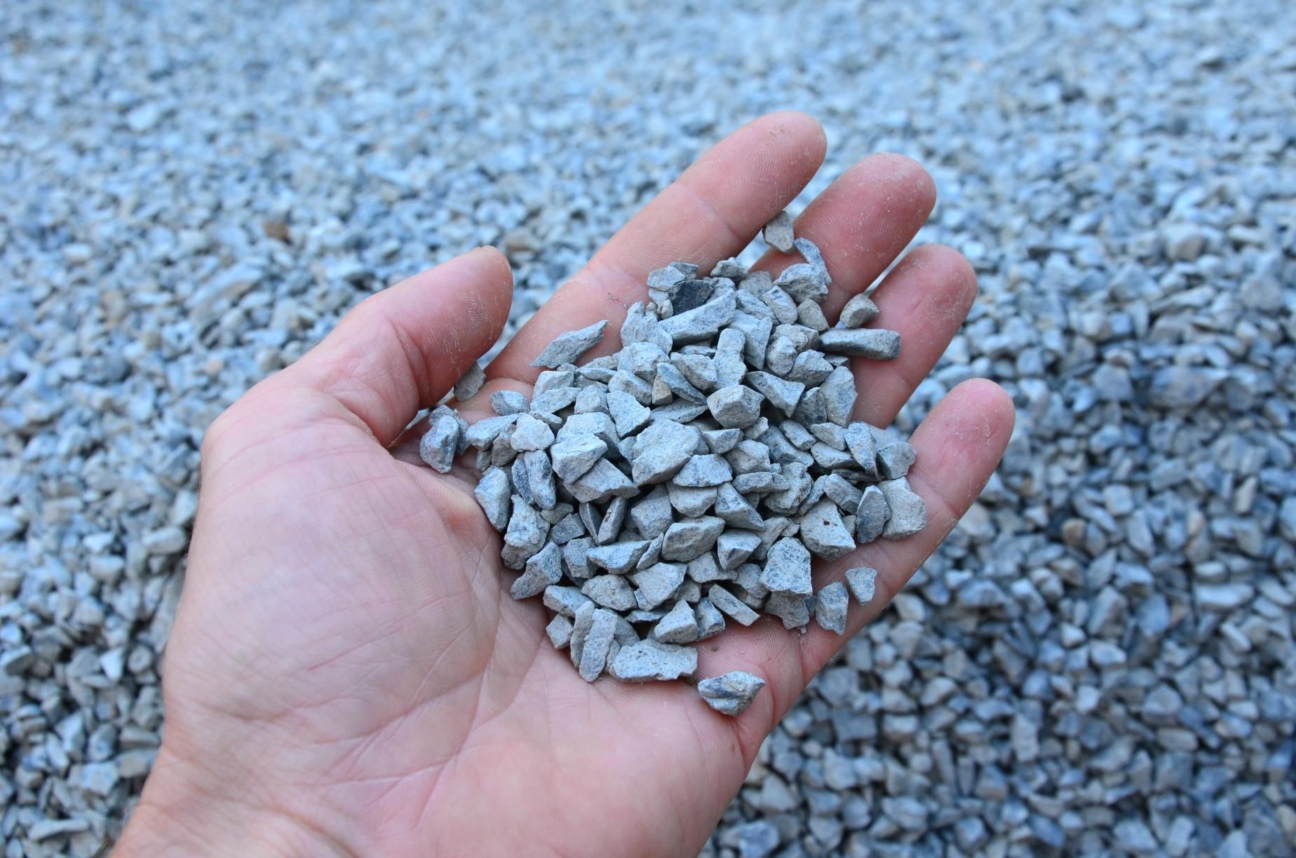A person is holding a pile of gravel in their hand.