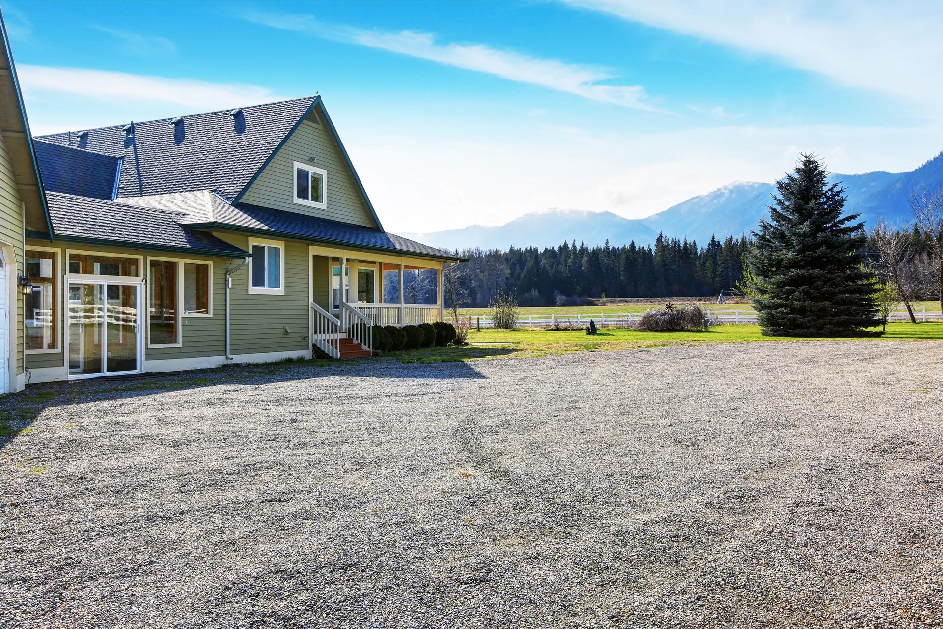 A large house with a gravel driveway in front of it.