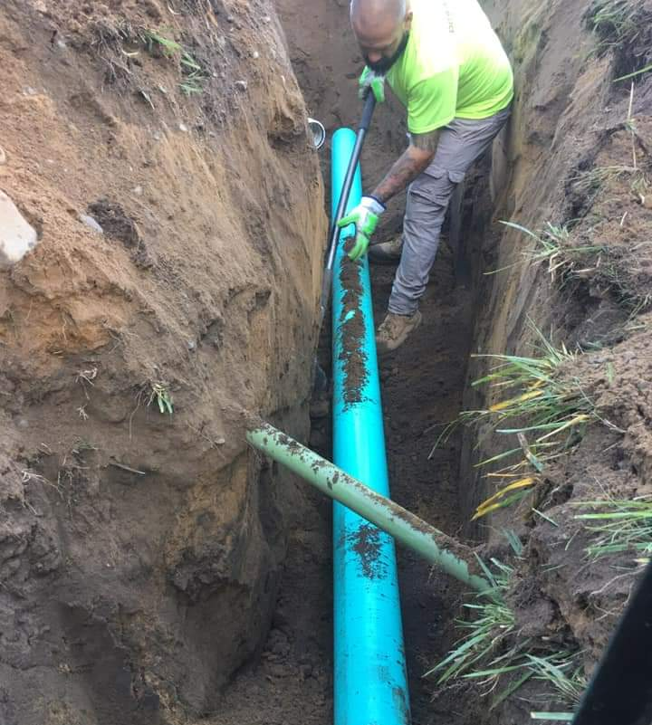 a man is digging a hole in the ground to install a pipe .