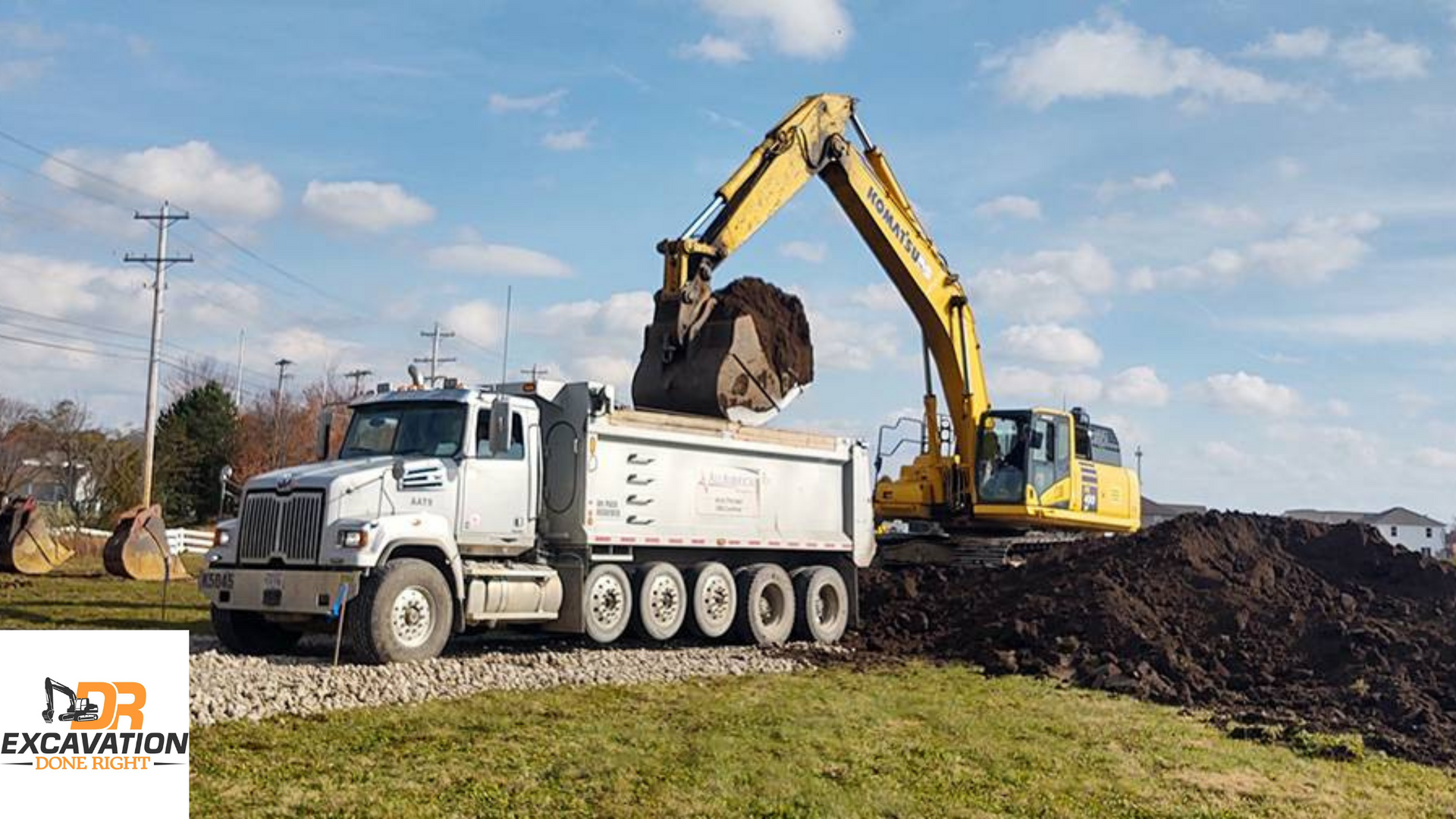 A dump truck is being loaded with dirt by an excavator.