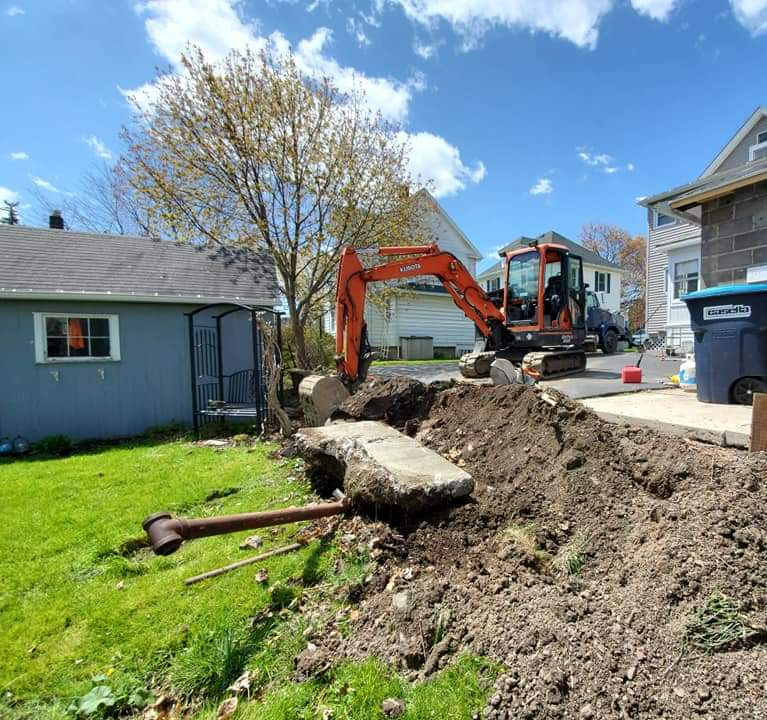 an orange excavator is digging a hole in front of a house .