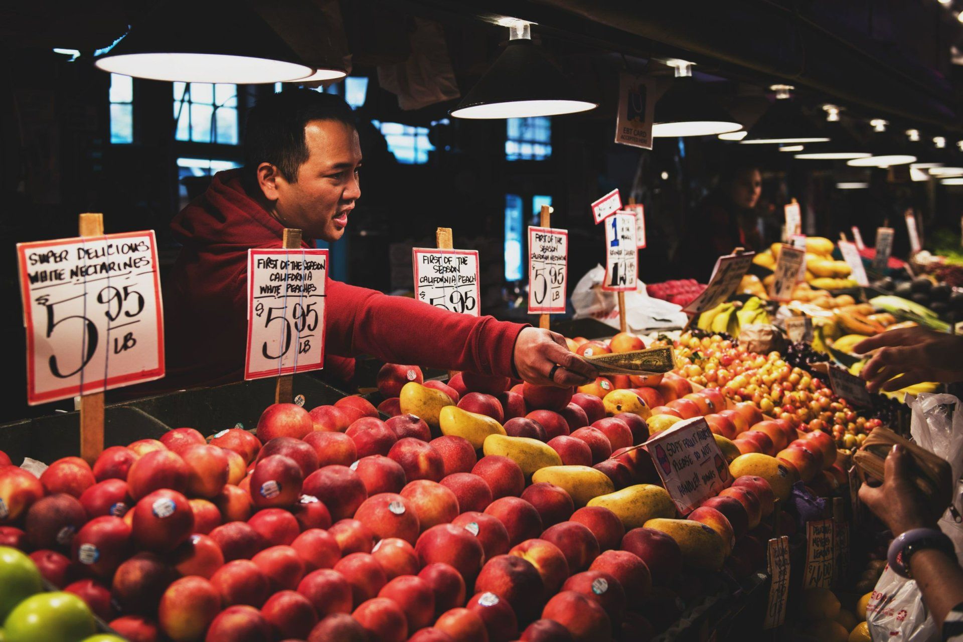a man stands in front of a fruit stand that sells apples for 95 cents