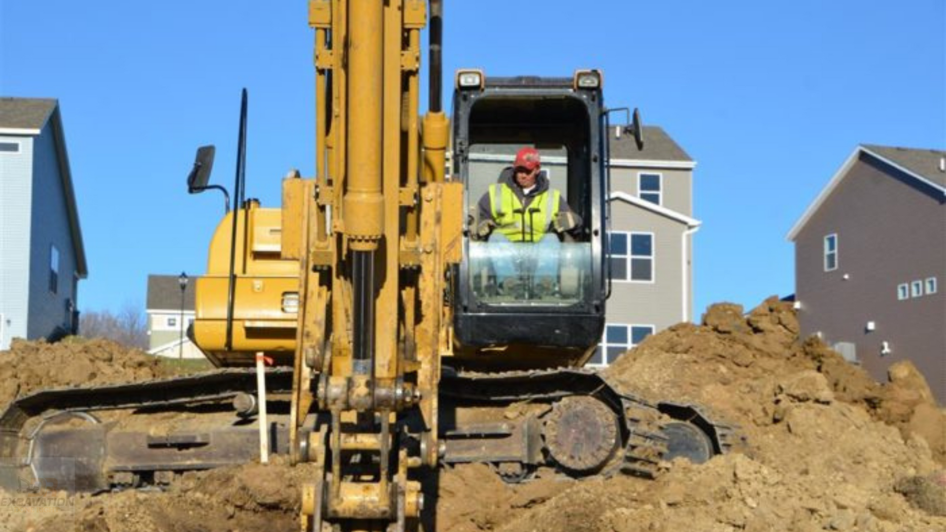 A man is driving a yellow excavator on a construction site.