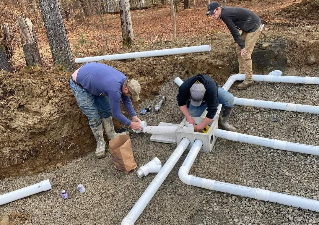 three men are working on a pipe system in the dirt
