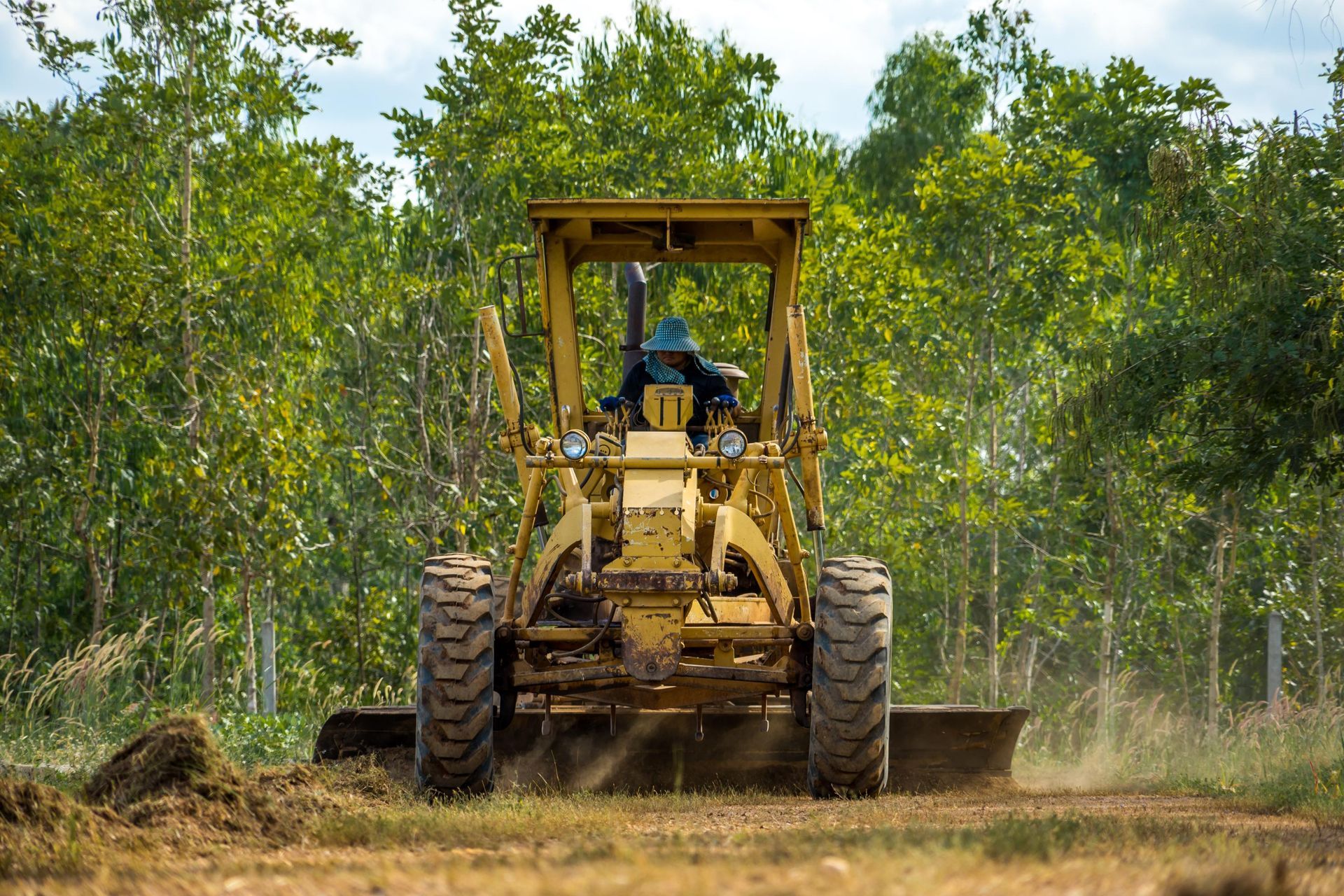 A man is driving a bulldozer through a dirt field.