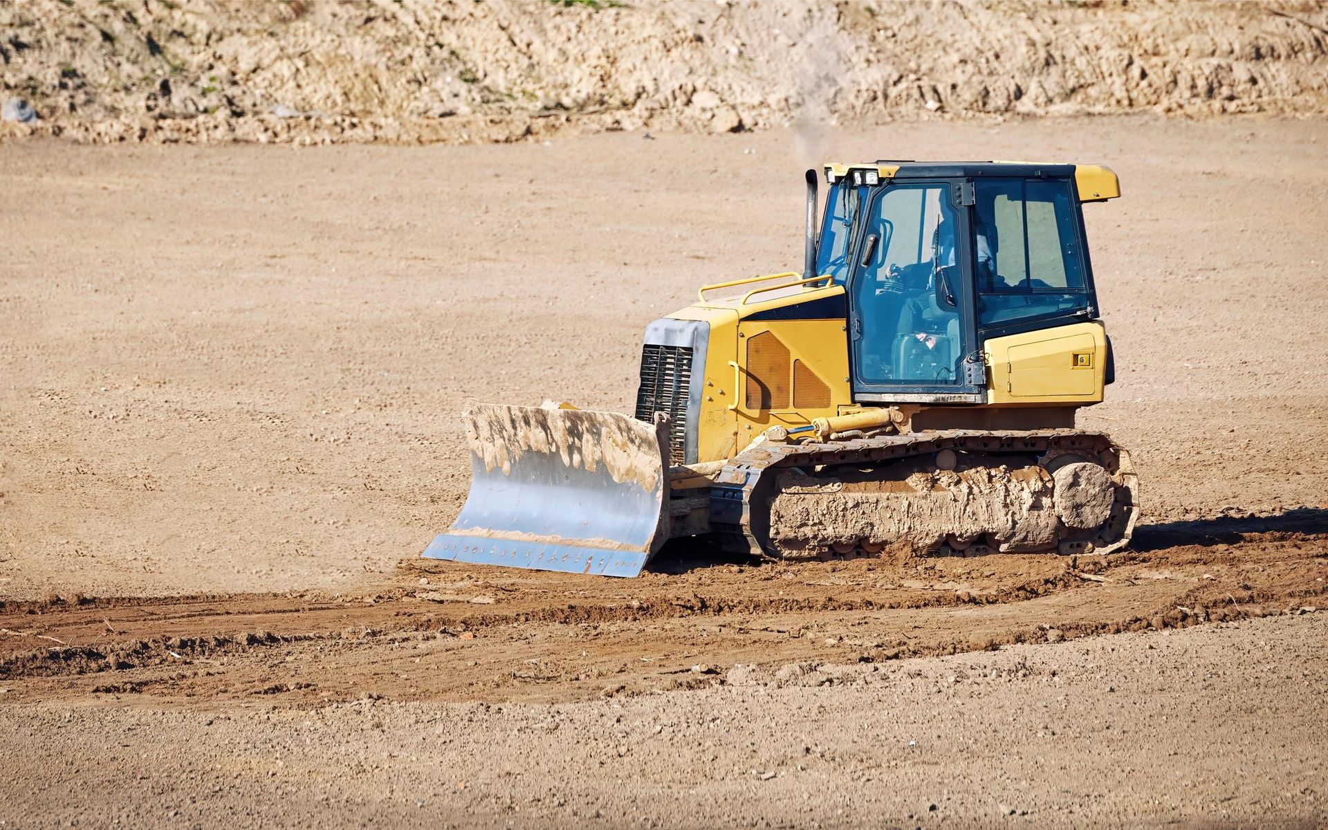 A bulldozer is driving through a dirt field.