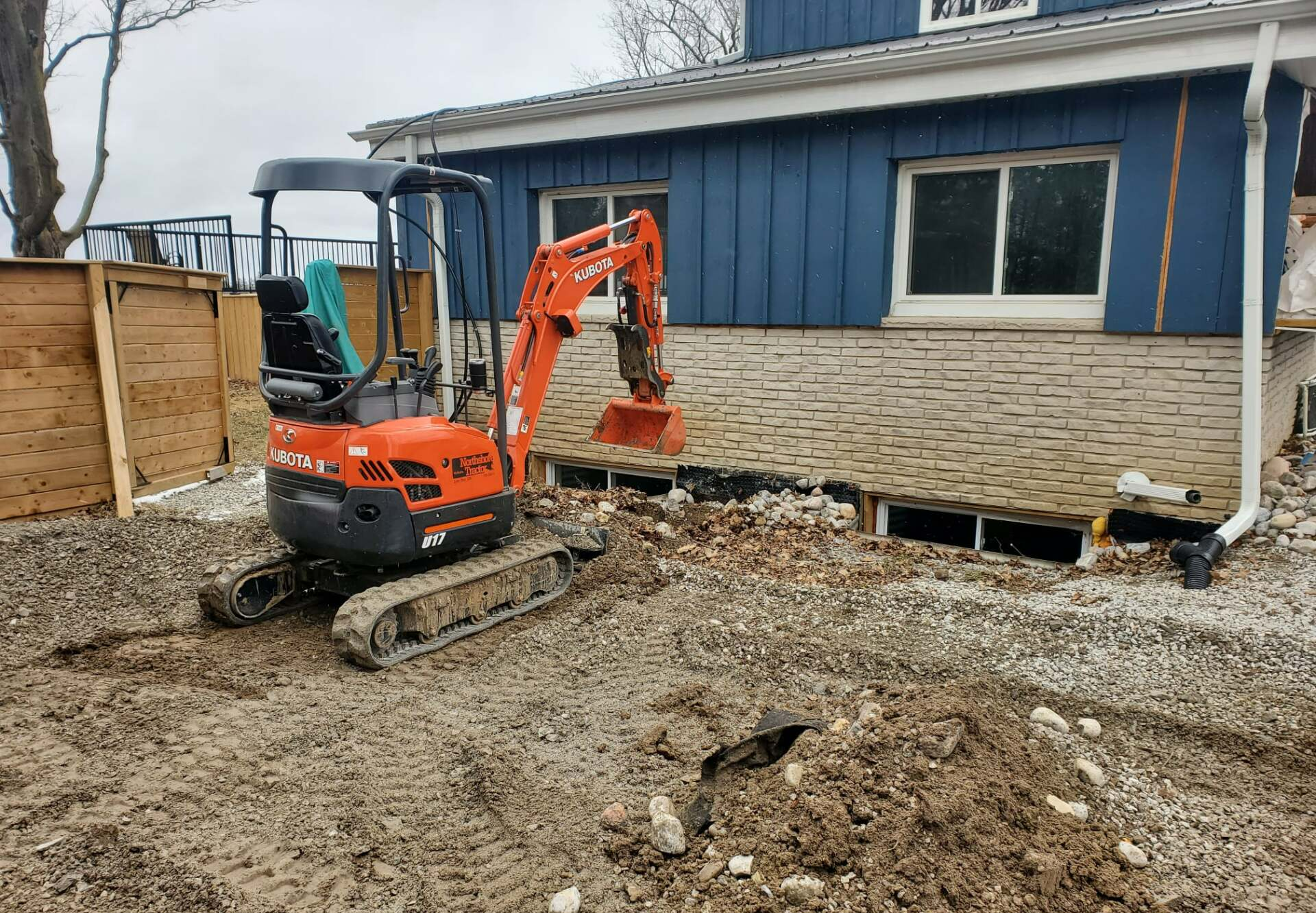 a small orange kubota excavator sits in front of a house
