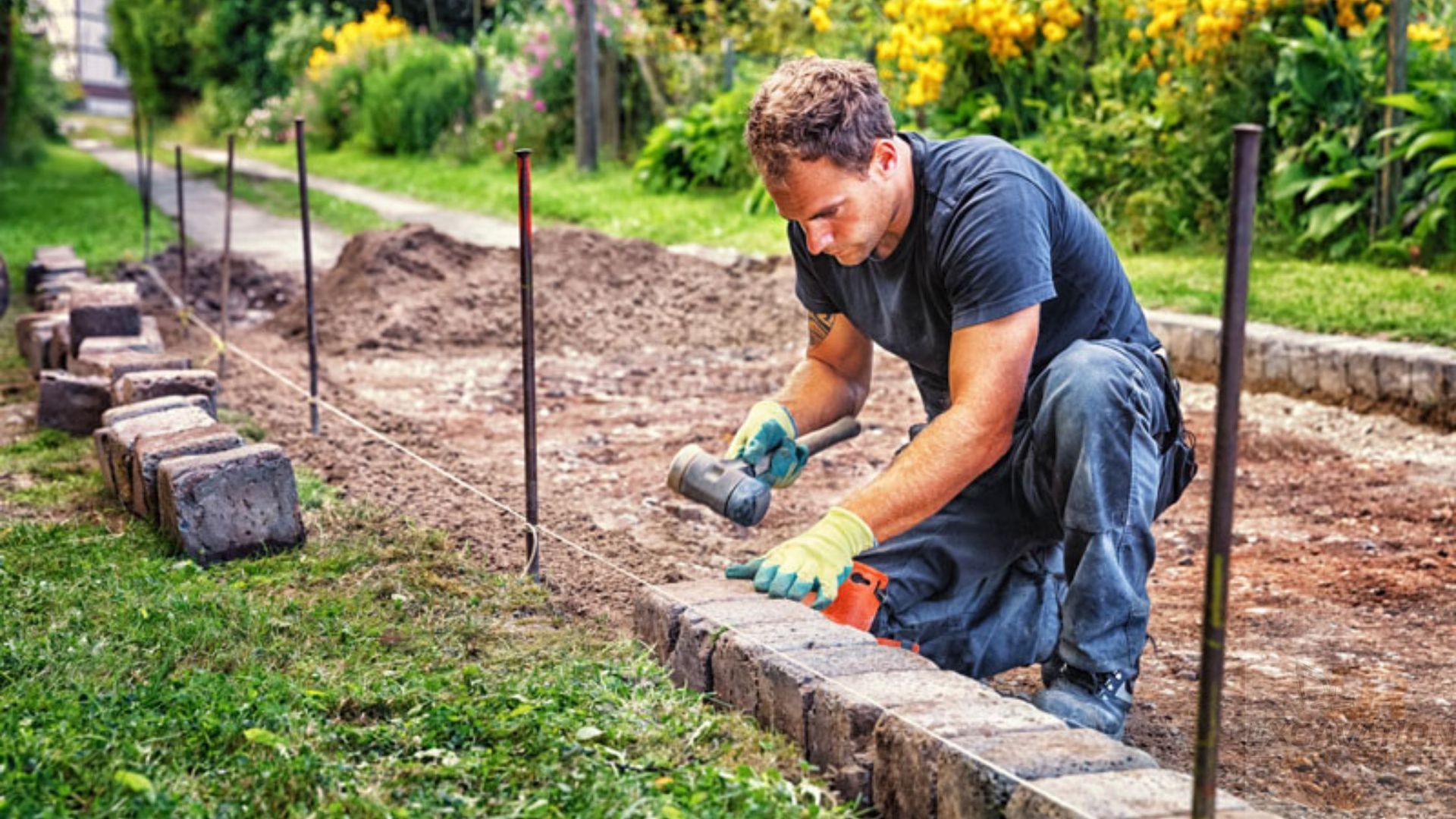 A man is kneeling down and working on a brick walkway.