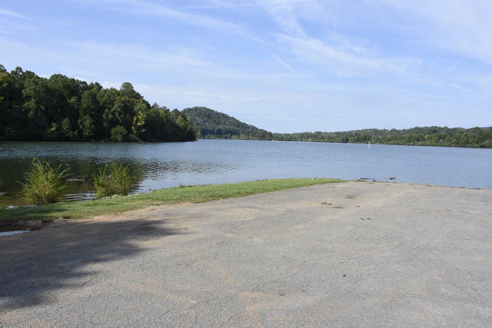 A large body of water surrounded by trees and a road.