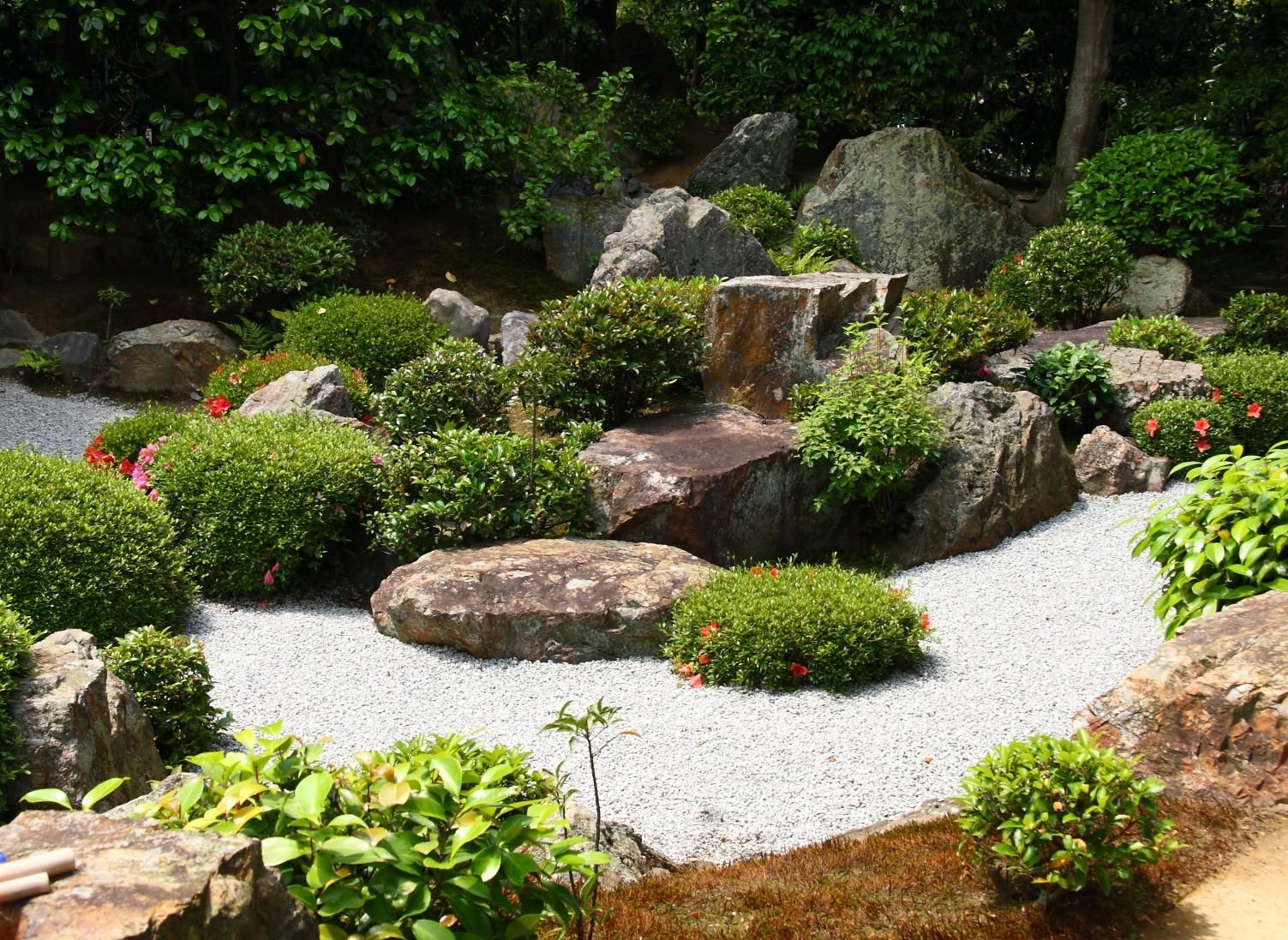 A garden with rocks , bushes and gravel in it