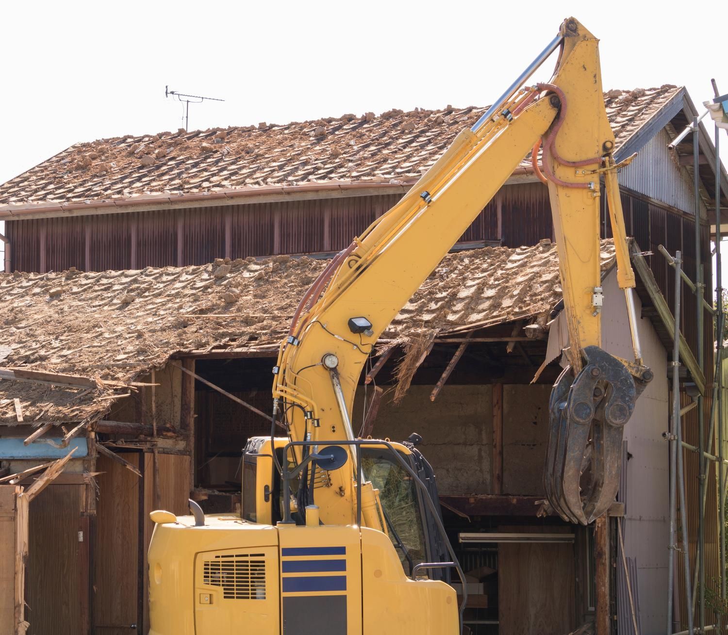 a large yellow excavator is demolishing a building