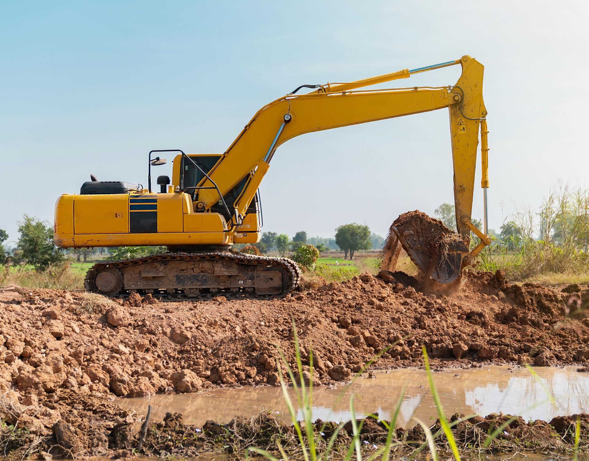 a yellow excavator is digging a hole in the dirt
