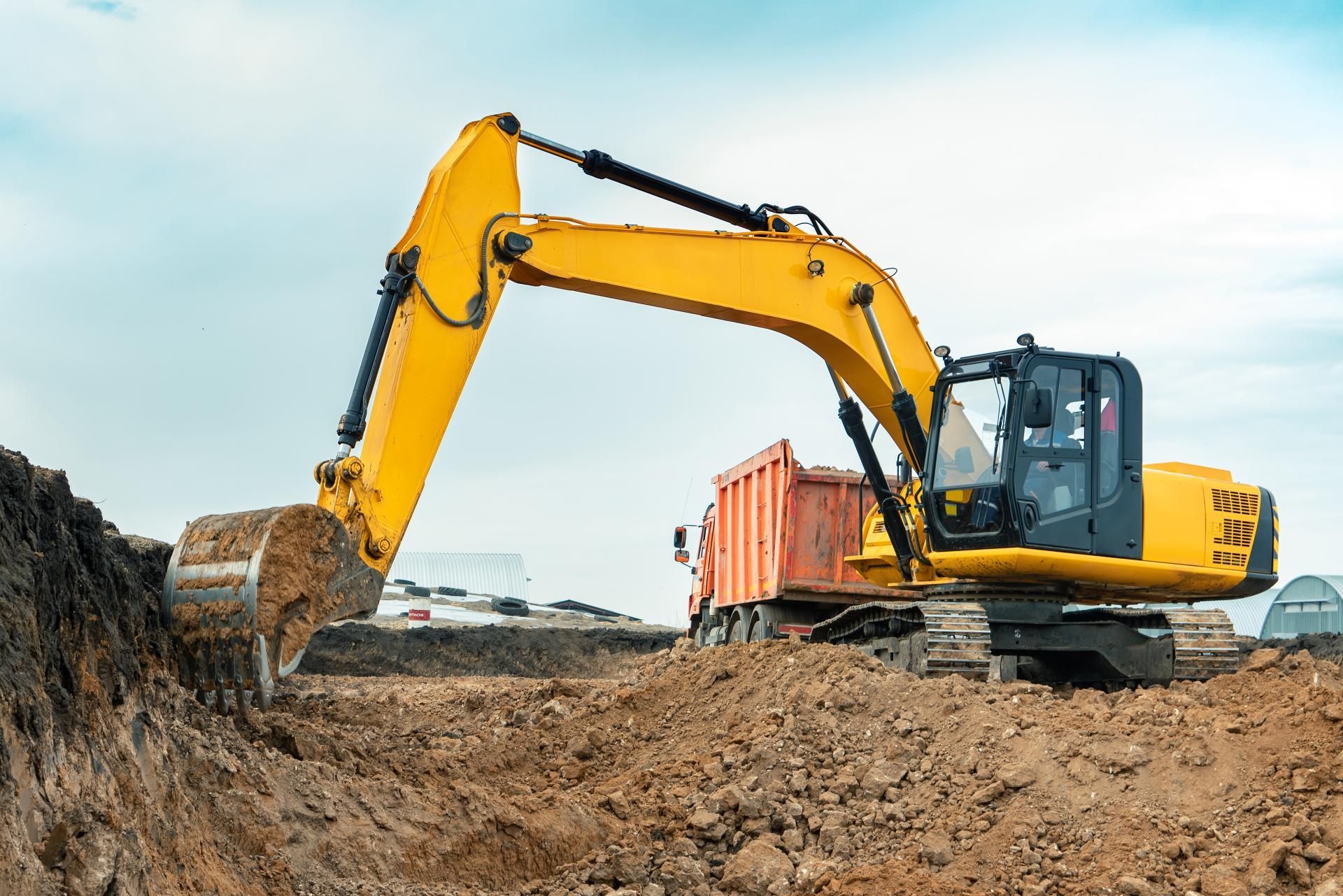 a yellow excavator is loading dirt into a dump truck