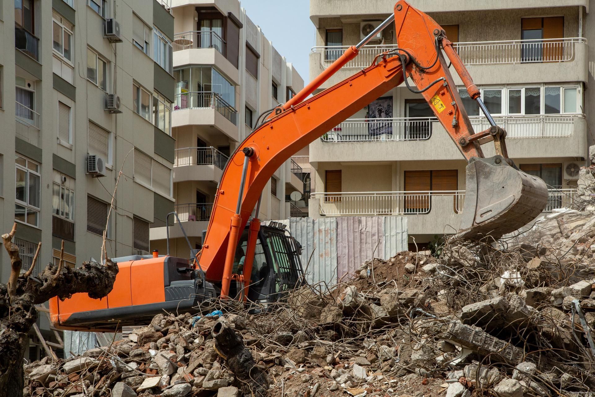 a large orange excavator is working on a pile of rubble
