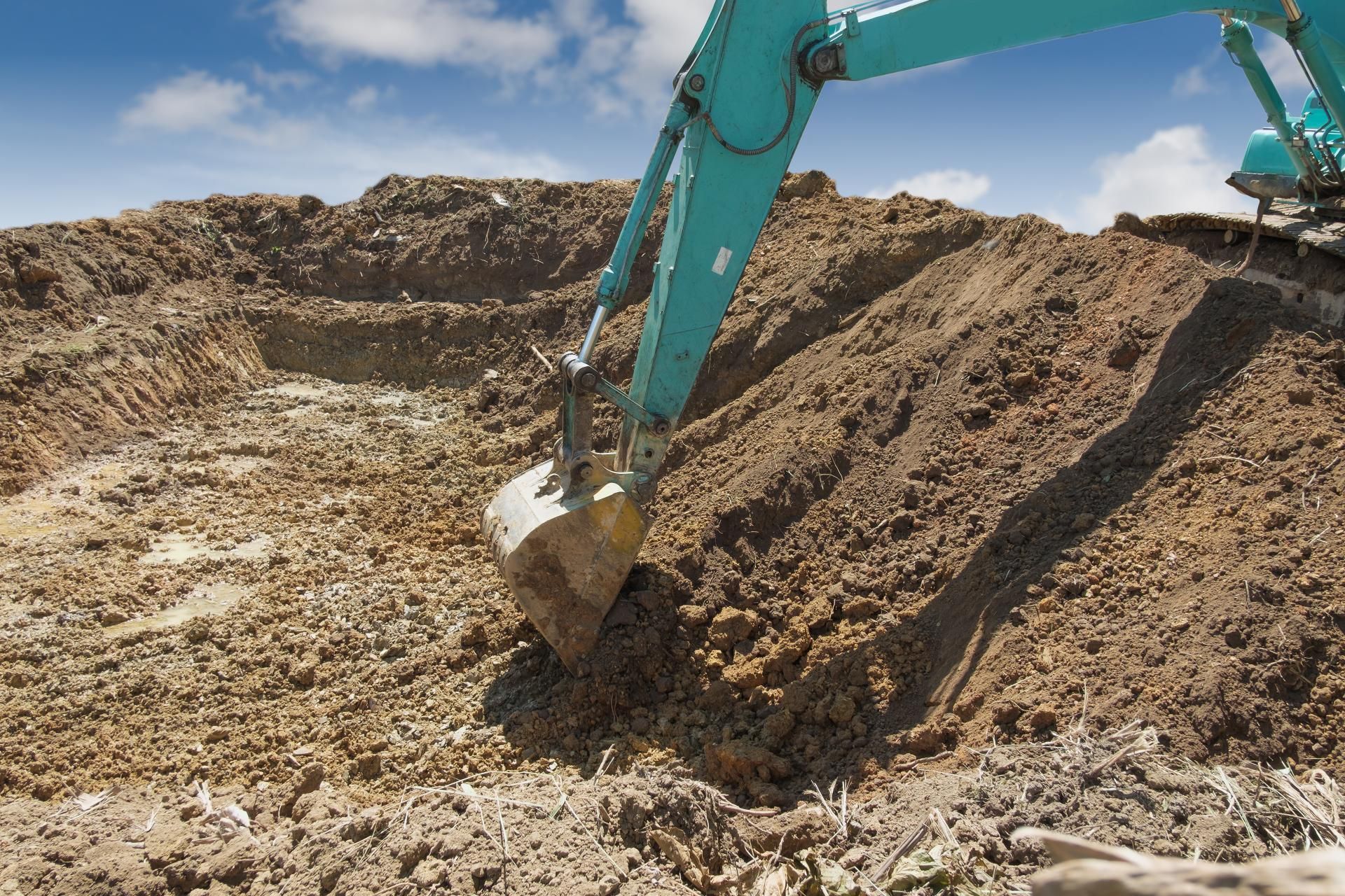a blue excavator is digging in a pile of dirt