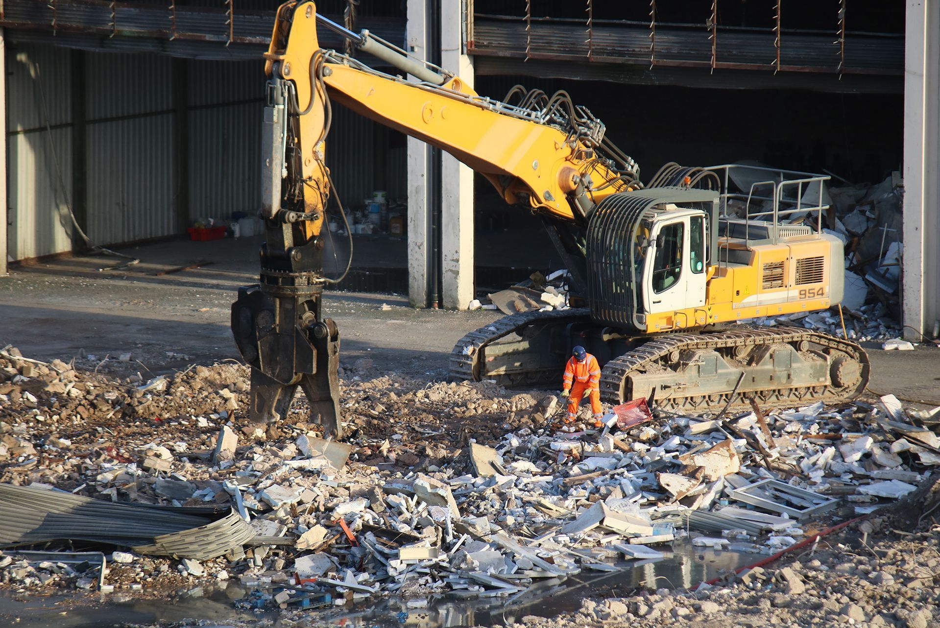 A large yellow excavator is working on a pile of rubble.