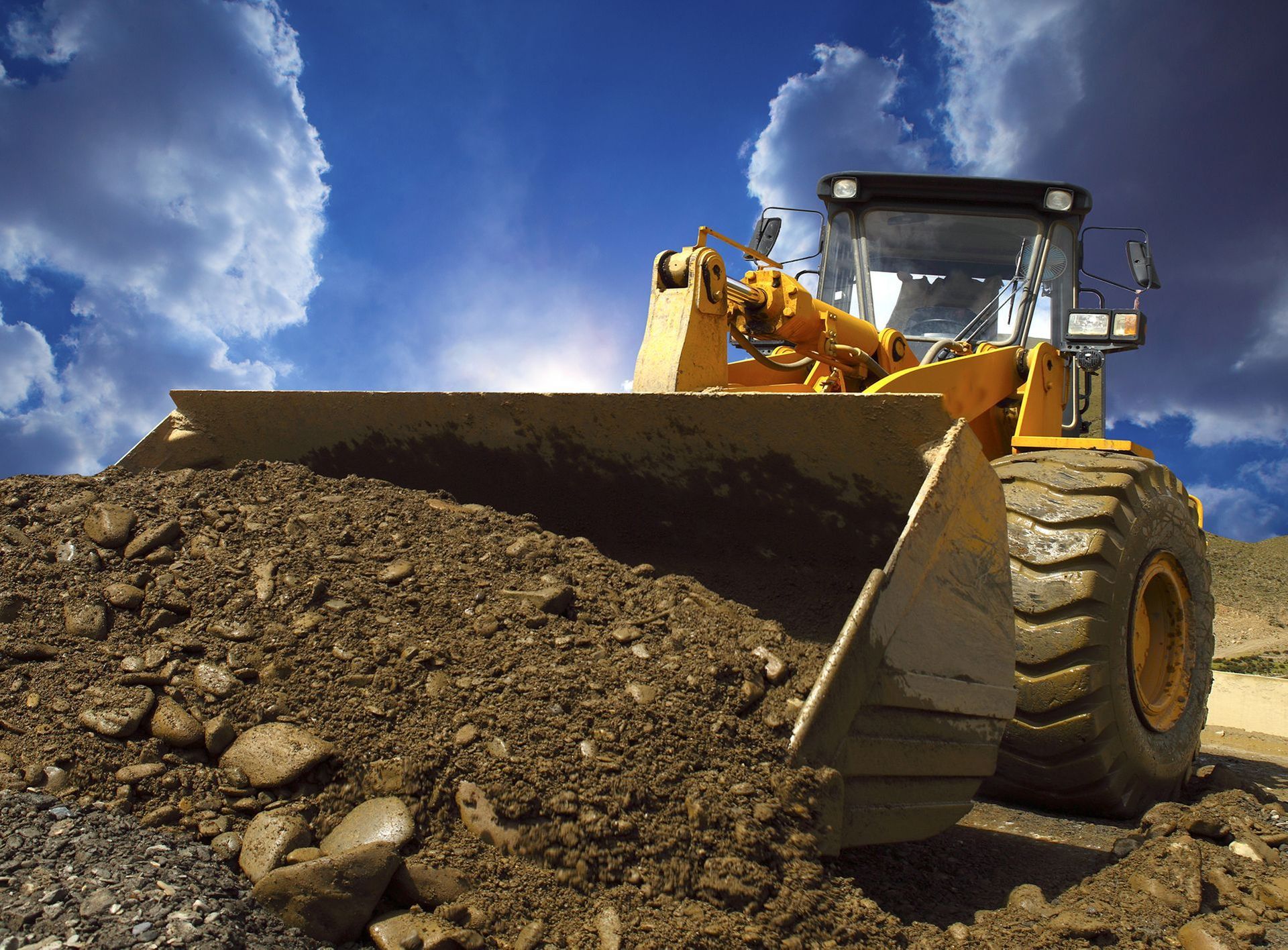 A bulldozer is scooping dirt from a pile of rocks
