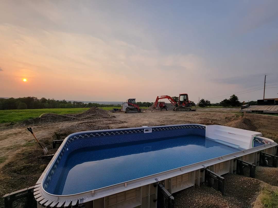 a large swimming pool is being built in a dirt field