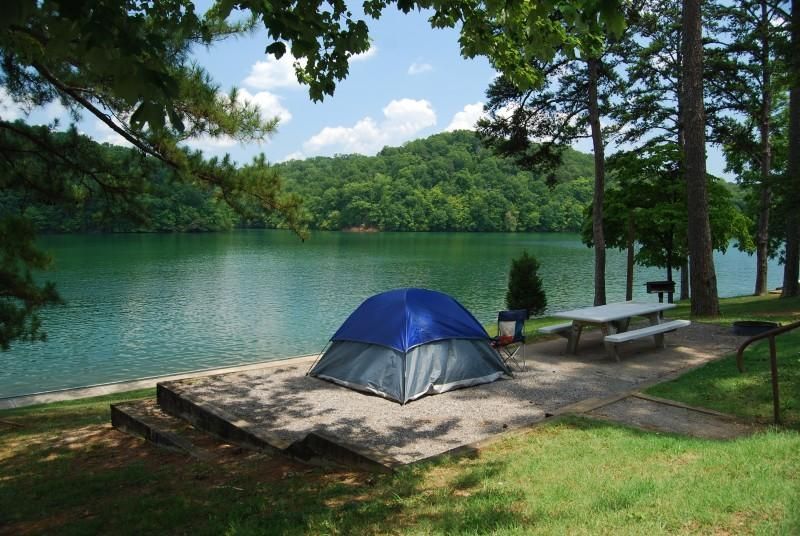 A blue tent is sitting on the shore of a lake