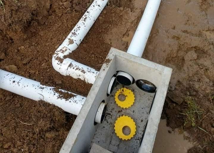 A bunch of pipes are connected to a box in the dirt.
