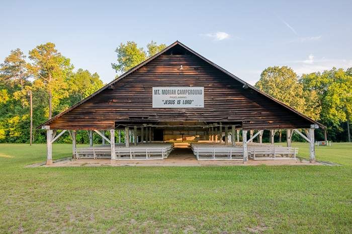 A large wooden building is sitting in the middle of a grassy field.