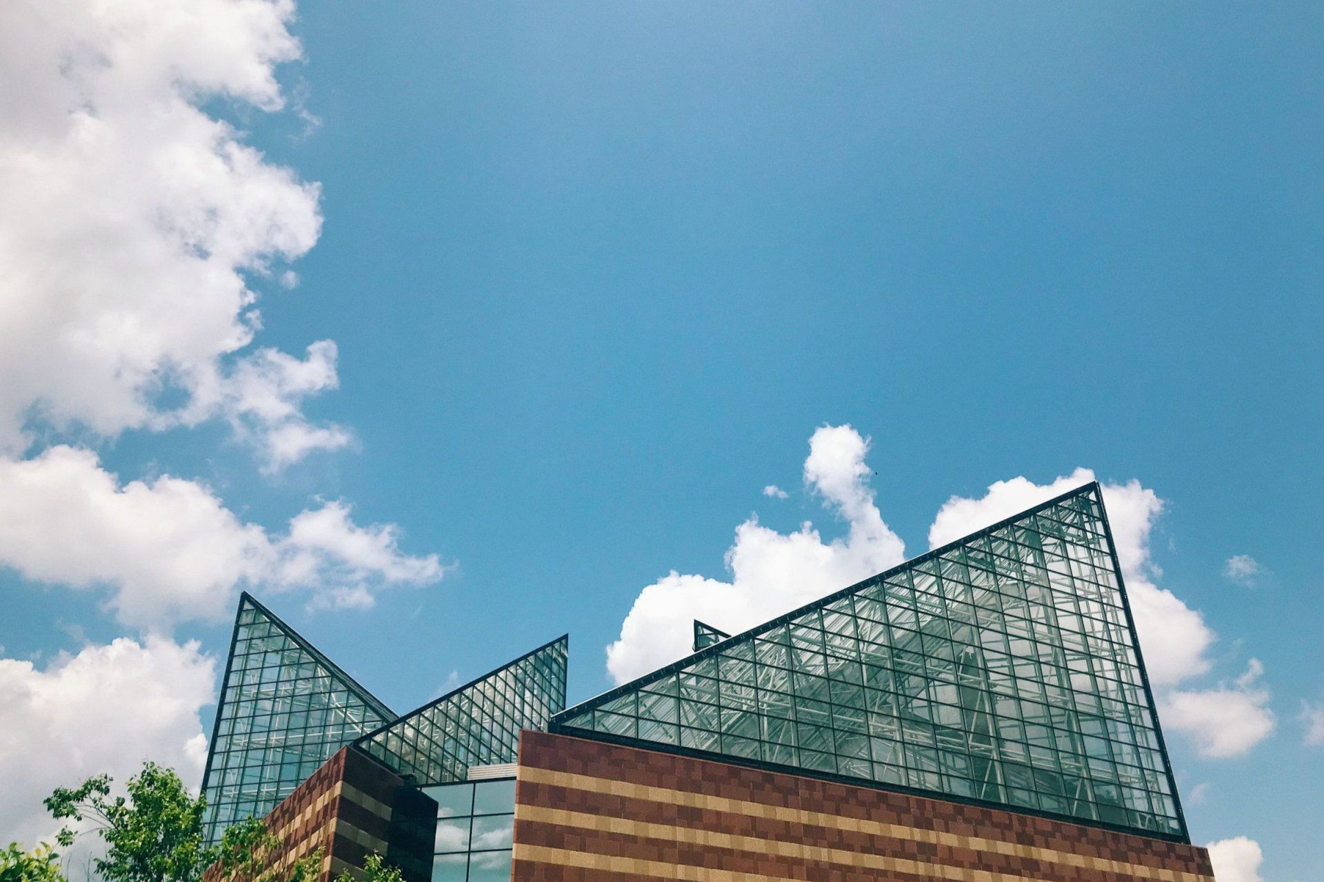 looking up at a building with a blue sky and clouds behind it