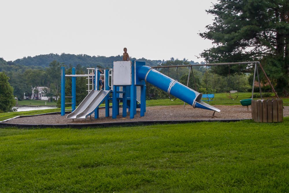 A blue and white playground with a slide and swings in a park.