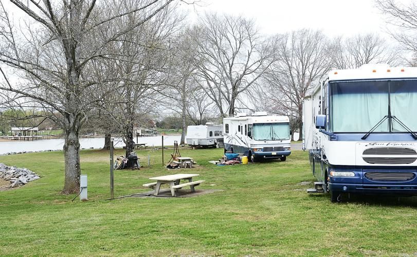 A rv is parked in a grassy field next to a picnic table.