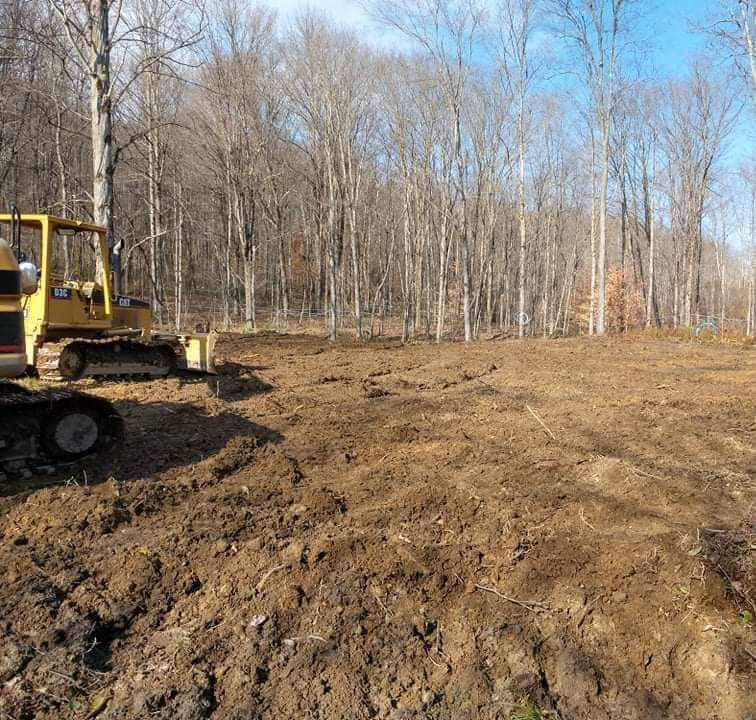 a yellow cat bulldozer is working in a muddy field