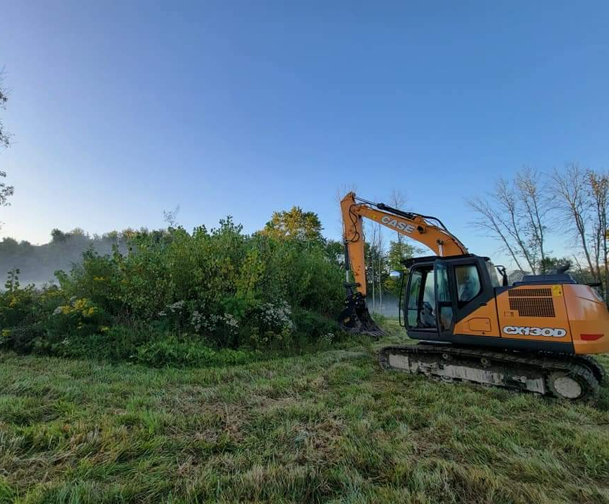a case excavator sits in a grassy field