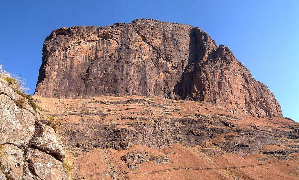 A large rocky mountain with a blue sky in the background