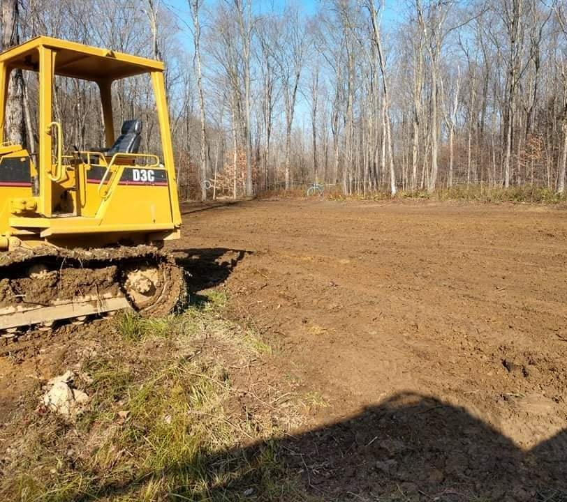 a yellow cat bulldozer is sitting in the middle of a dirt field
